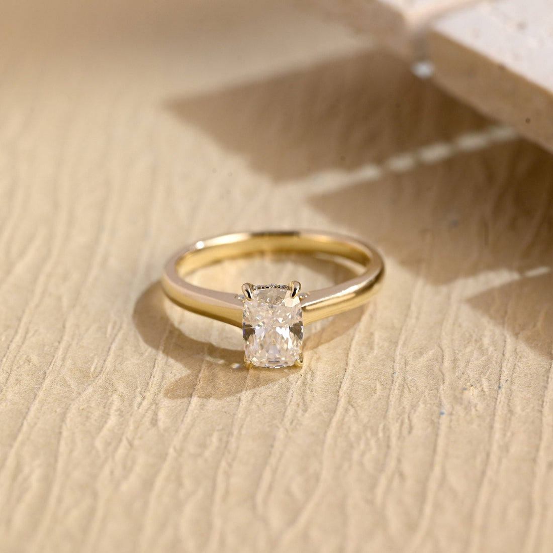 Elongated cushion moissanite hidden halo engagement ring in four claws on a smooth tapered yellow gold band