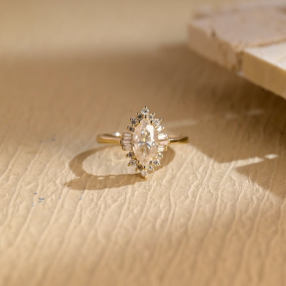Art deco marquise cut moissanite halo engagement ring with baguette side clusters on a yellow gold band