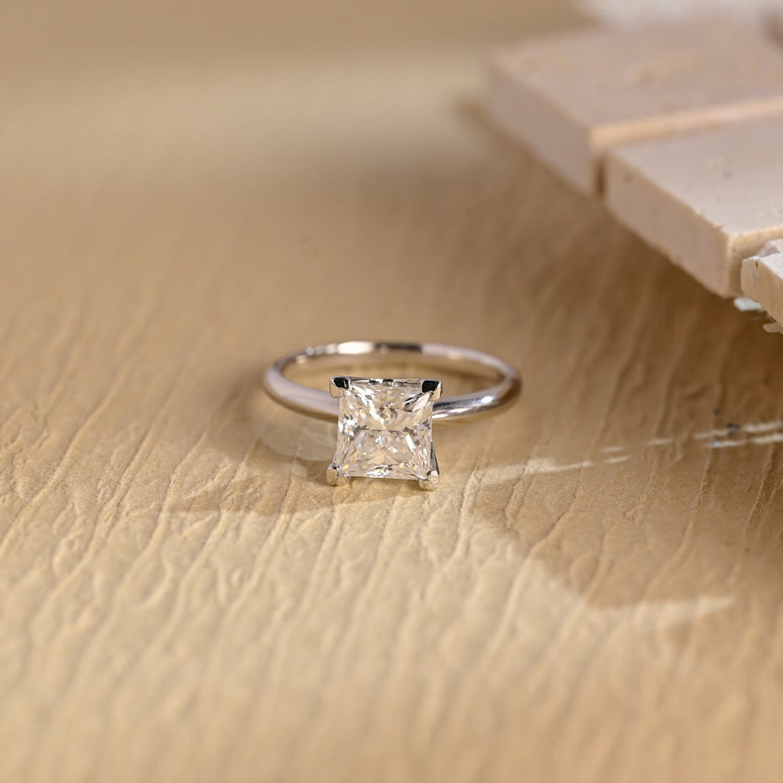 Princess cut moissanite classic four claw solitaire engagement ring on a slim polished white gold band