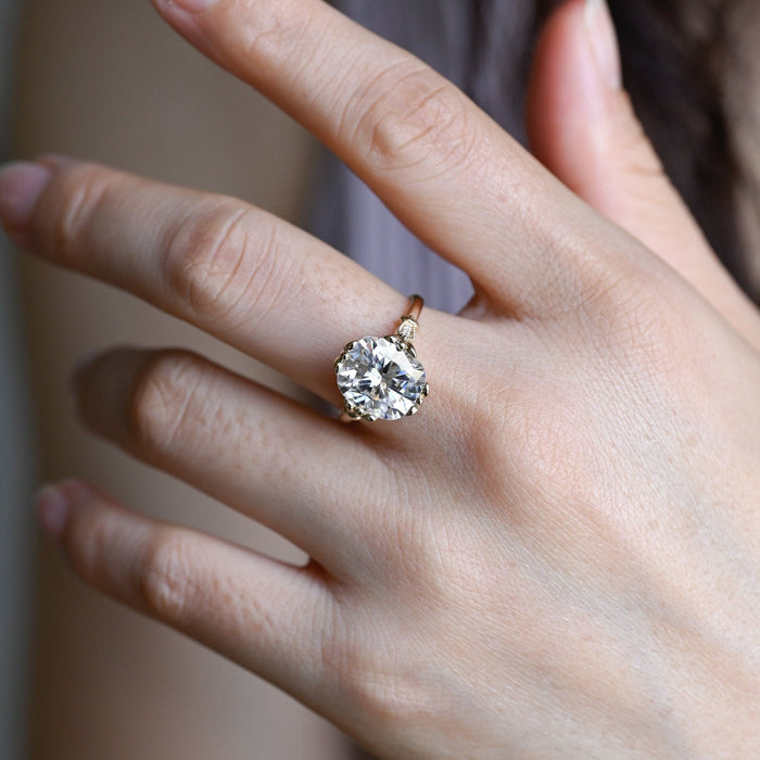 Elongated cushion moissanite vintage engagement ring with four ornate floral claws and milgrain shoulders set with small round stones on a yellow gold band, view 2
