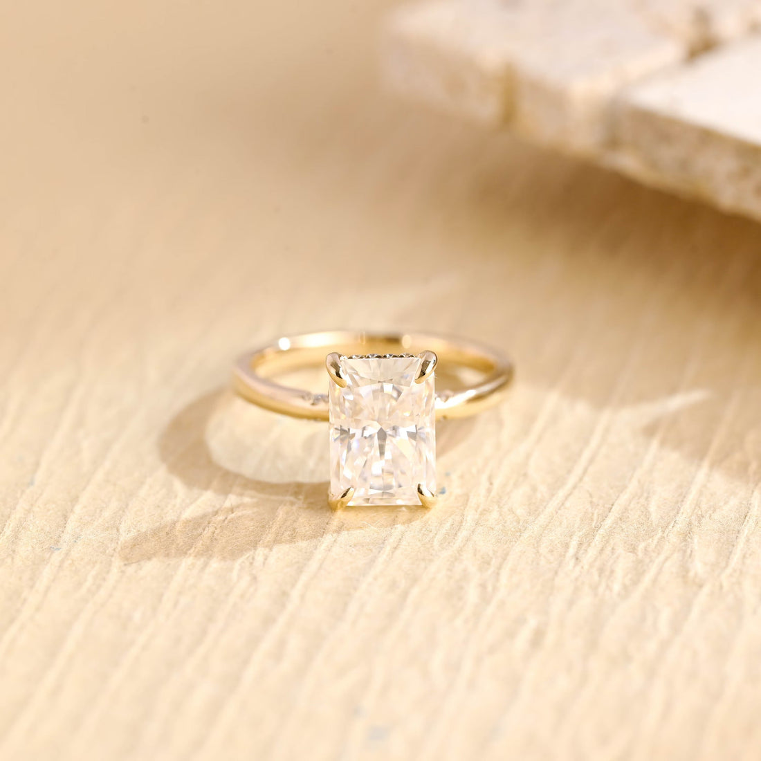 Statement radiant cut moissanite hidden halo engagement ring in four claws with tiny stones set in the shoulders of a slim yellow gold band
