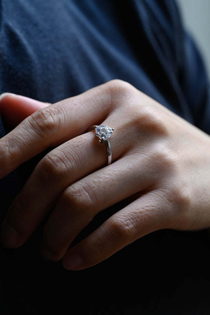 Classic heart cut moissanite solitaire engagement ring in a three claw setting on a slim plain white gold band, view 2