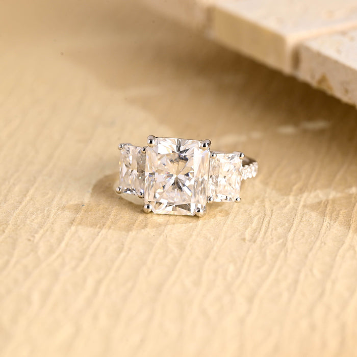 Radiant cut moissanite three stone engagement ring with two radiant side stones in four claws on a pave set white gold band