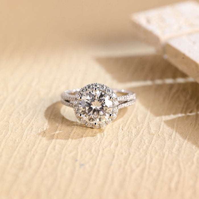 Round moissanite halo engagement ring in six claws with a fine split shank of two slender pave set strands in white gold