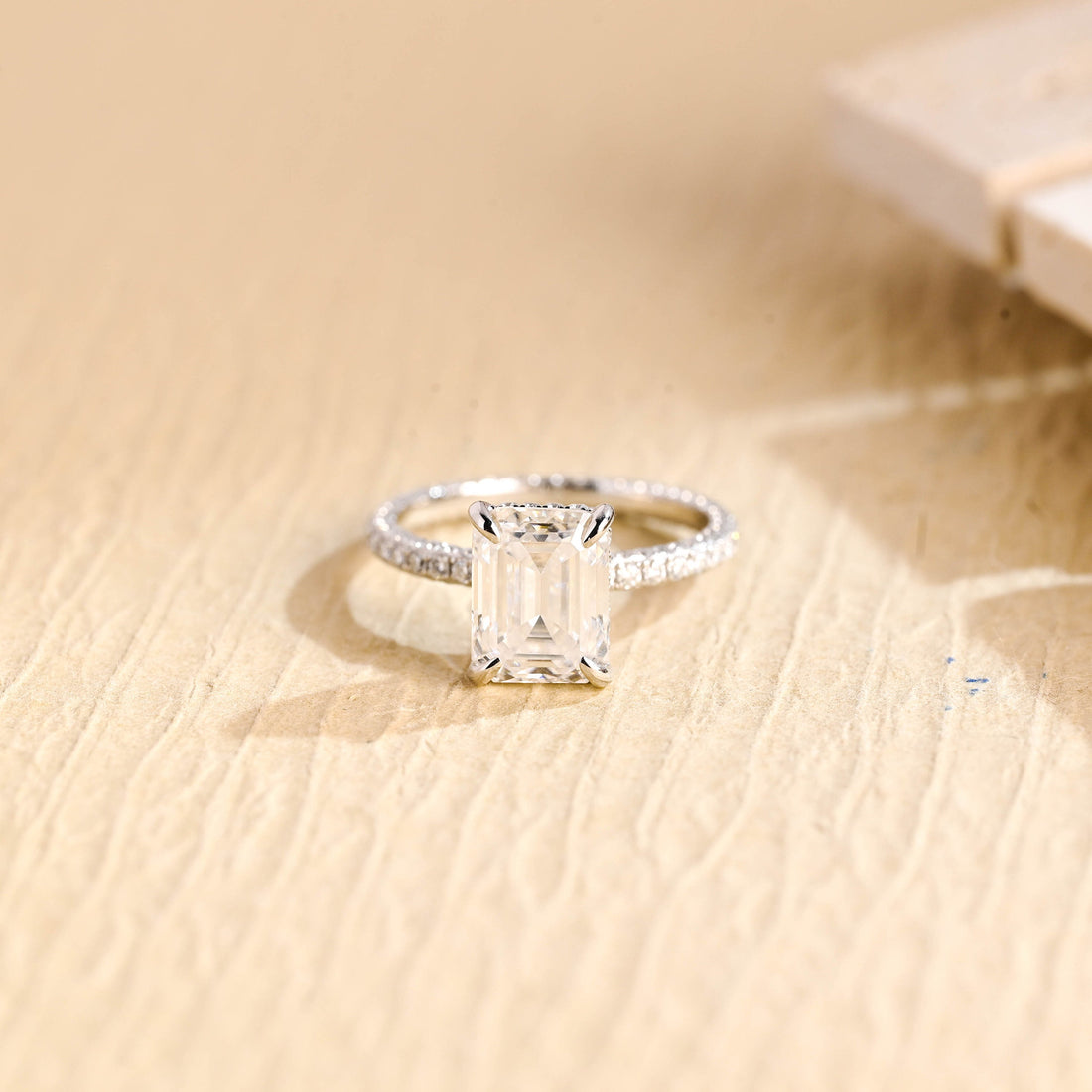 Emerald cut moissanite hidden halo engagement ring with four claws and a fine micro pave white gold band