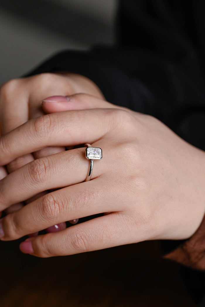Bezel set radiant cut moissanite solitaire engagement ring on a plain polished white gold band, view 2