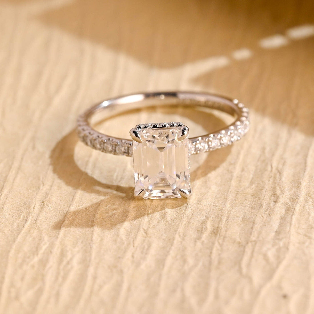 Emerald cut moissanite hidden halo engagement ring with a pave set band in white gold