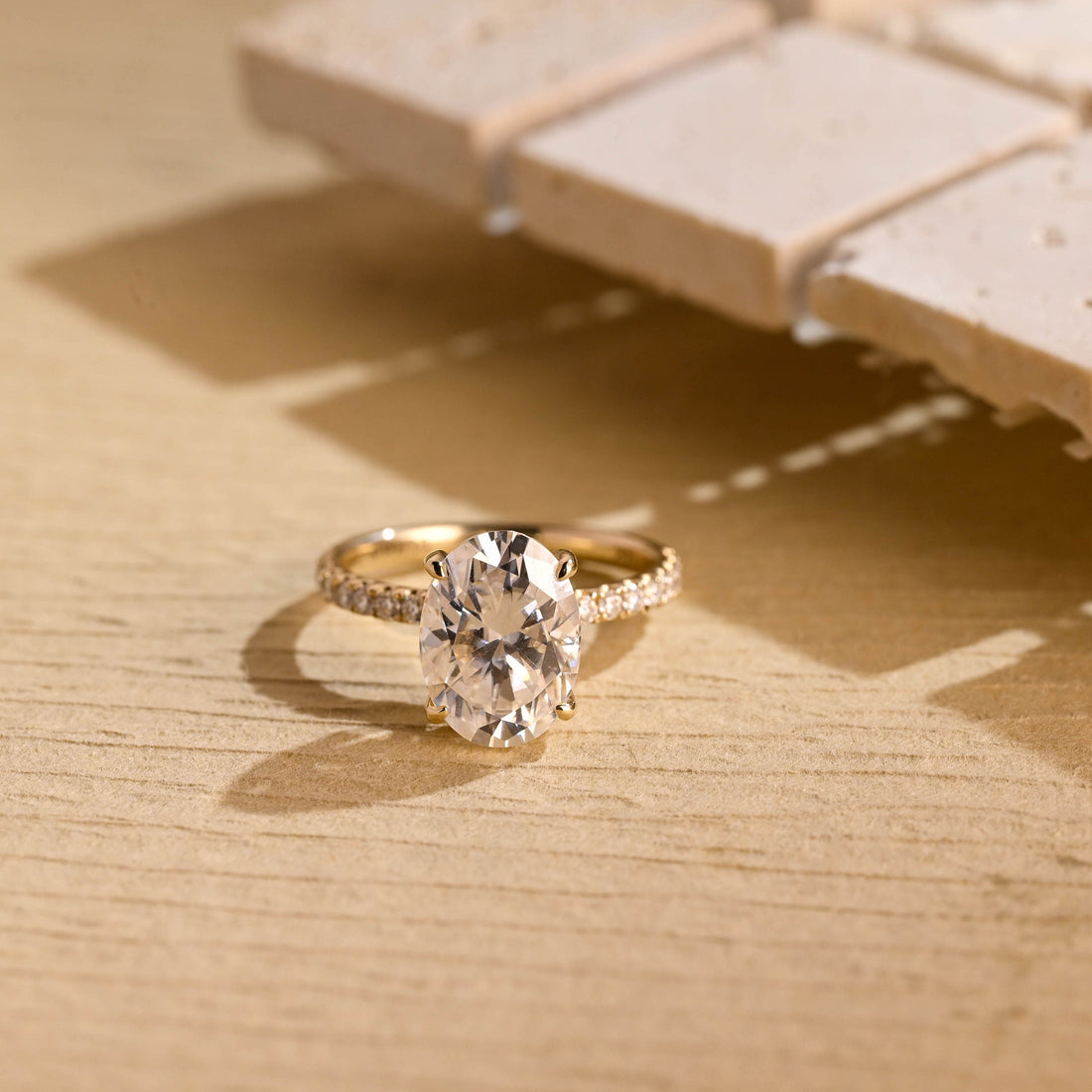Large oval moissanite engagement ring with four claws and a scallop set pave round stone band in yellow gold