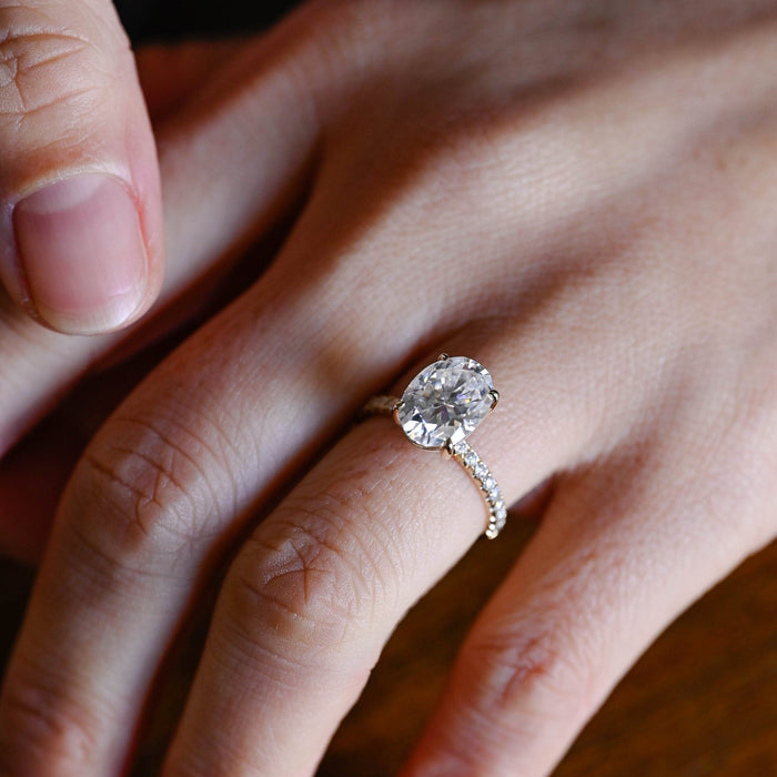Large oval moissanite engagement ring with four claws and a scallop set pave round stone band in yellow gold, view 2