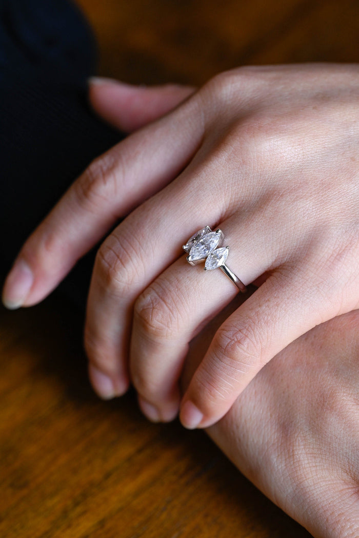 Three marquise cut moissanite engagement ring with staggered side stones on a plain white gold band, view 2