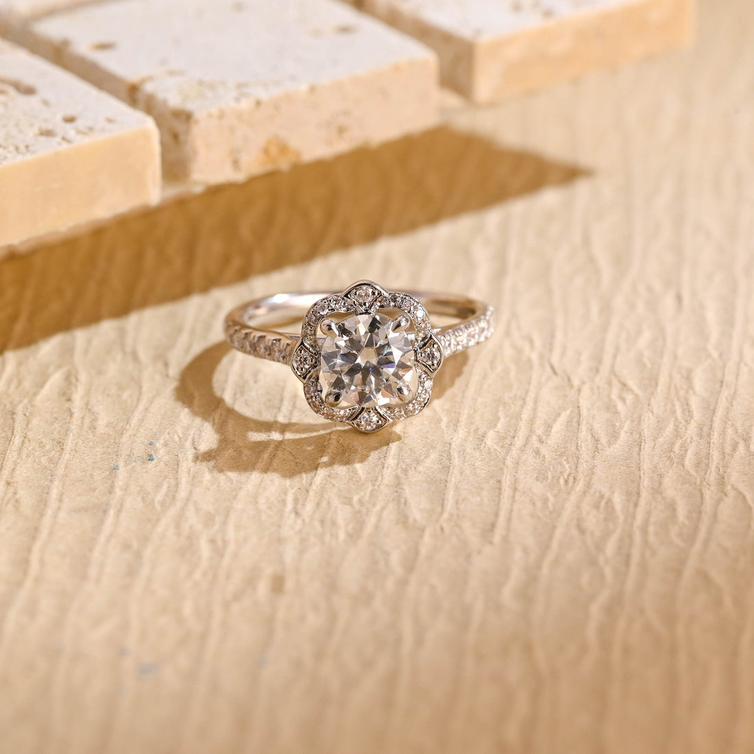 Round moissanite engagement ring with a scalloped flower shaped pave halo and a pave set band in white gold