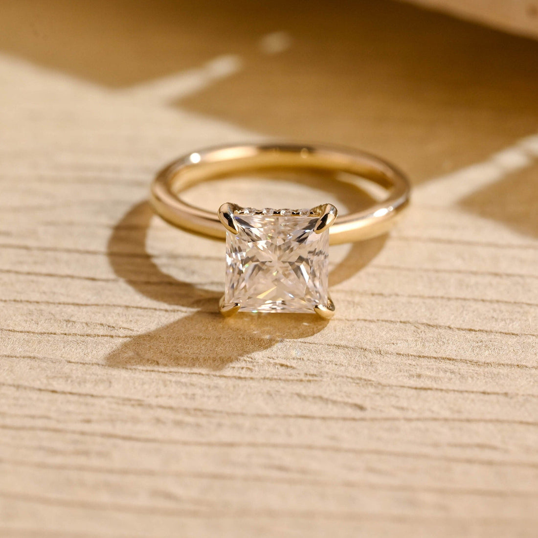 Princess cut moissanite hidden halo solitaire engagement ring on a plain yellow gold band