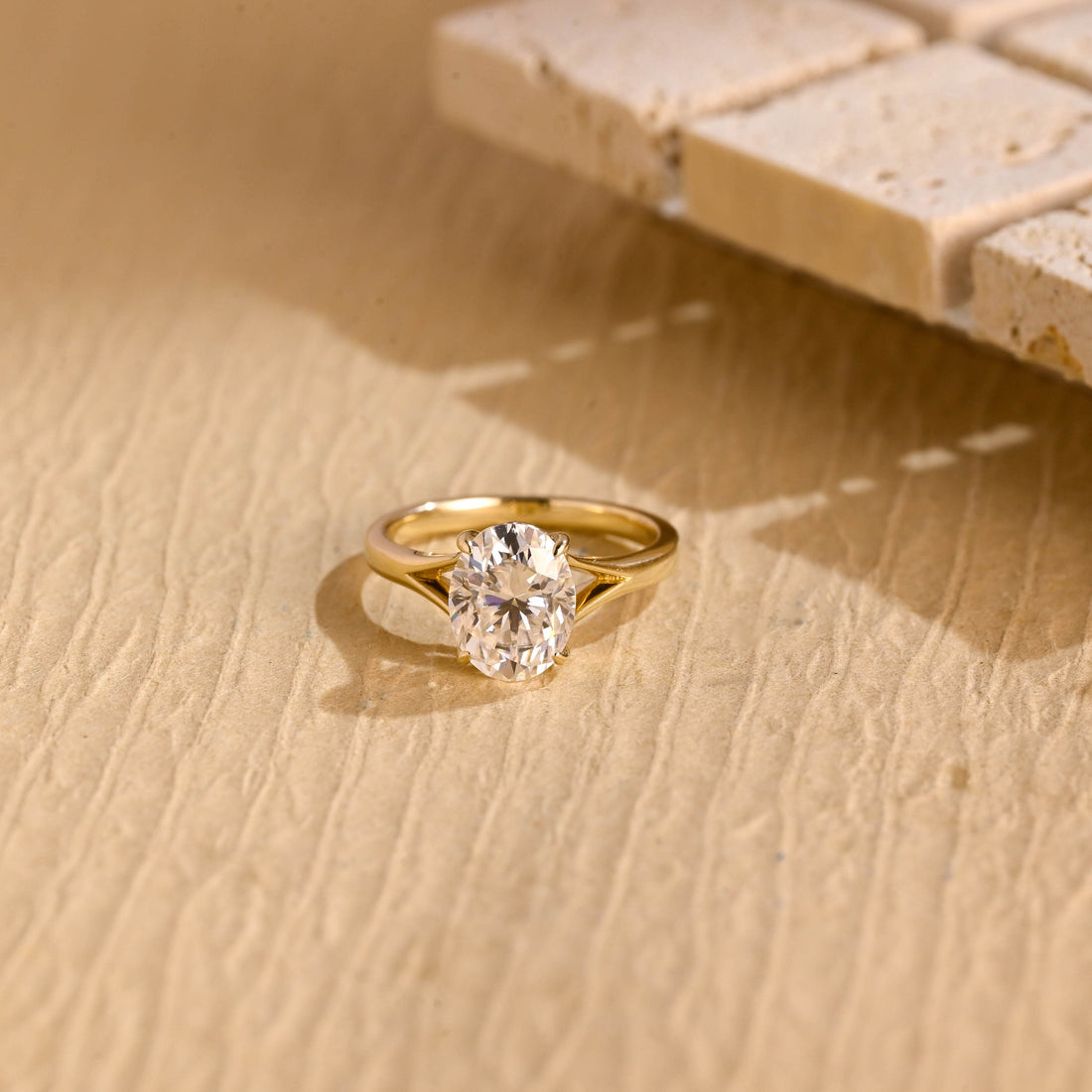 Oval moissanite solitaire engagement ring in four slim claws on a polished yellow gold split shank band