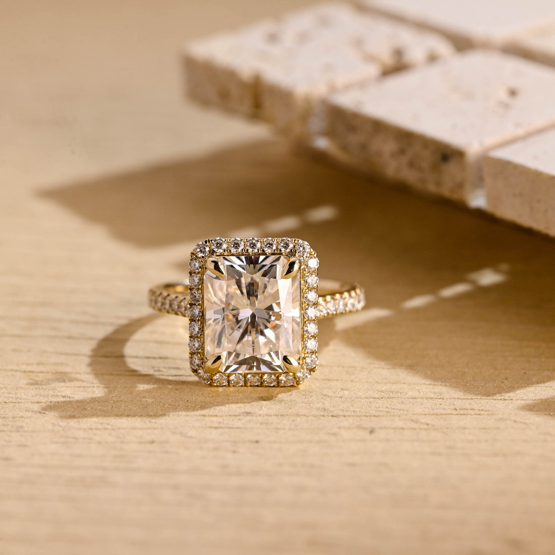 Radiant cut moissanite halo engagement ring in four claws with a pave set yellow gold band