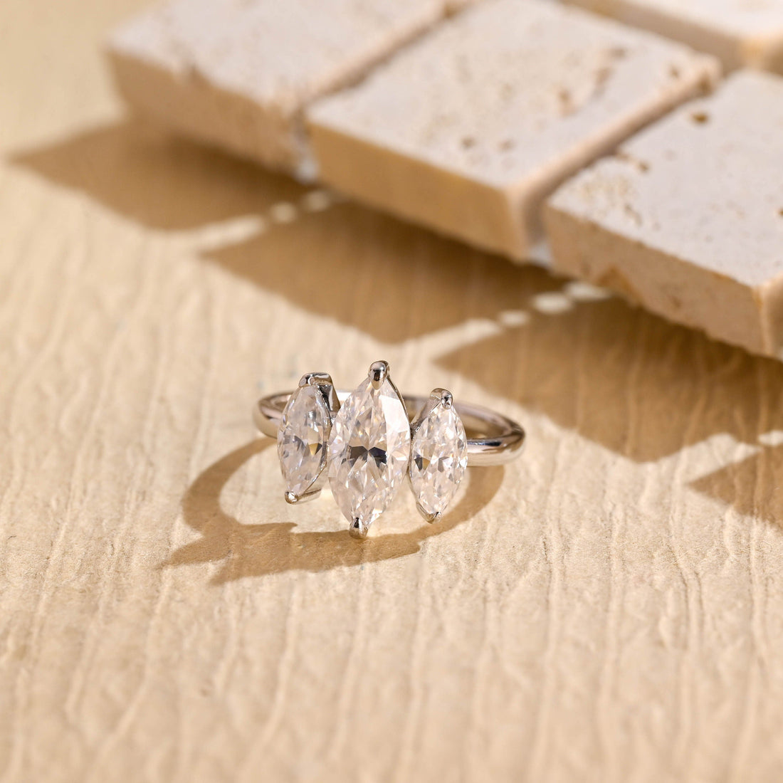 Three marquise cut moissanite engagement ring with staggered side stones on a plain white gold band