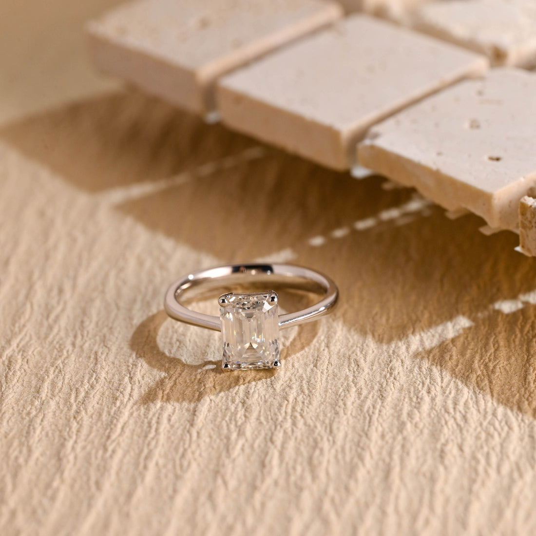Elongated emerald cut moissanite solitaire engagement ring in four slim claws on a fine polished white gold band