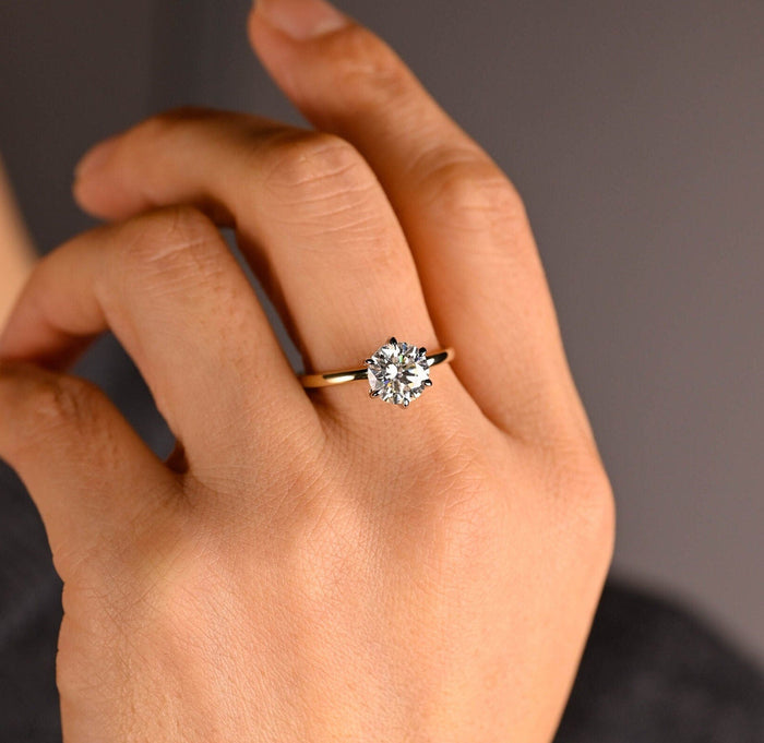 Round moissanite hidden halo engagement ring in six white claws on a slim polished yellow gold band, view 2