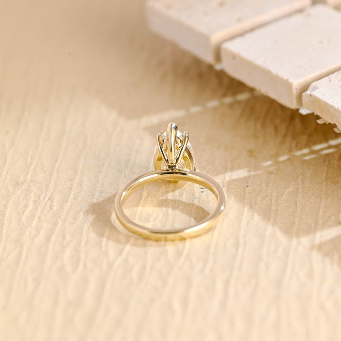 Large pear moissanite solitaire engagement ring with a V tip claw at the point and four ball claws on a polished yellow gold band, view 2