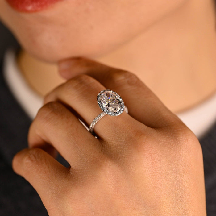 Elongated oval moissanite micro pave halo engagement ring with a band set with tiny stones across the top and down both sides in white gold, view 2
