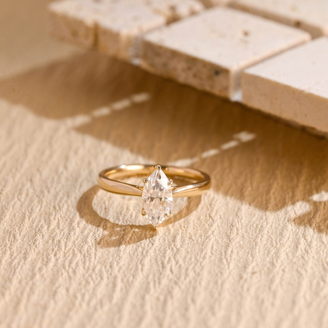 Marquise cut moissanite cathedral six claw solitaire engagement ring on a tapered polished yellow gold band
