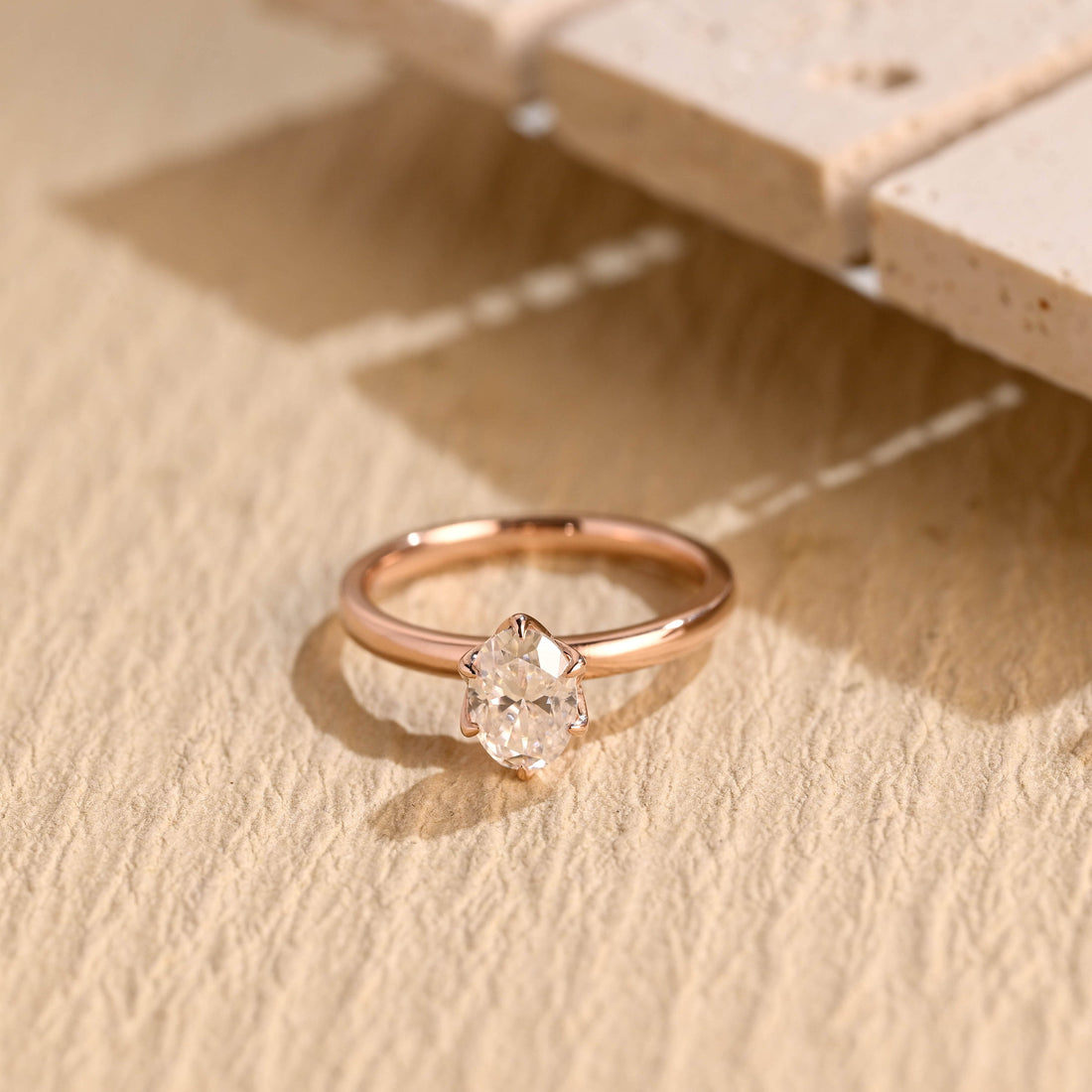 Oval moissanite solitaire engagement ring held by six slim claws on a slim polished rose gold band