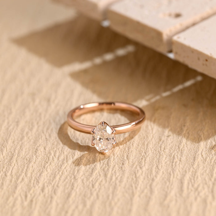 Oval moissanite solitaire engagement ring held by six slim claws on a slim polished rose gold band
