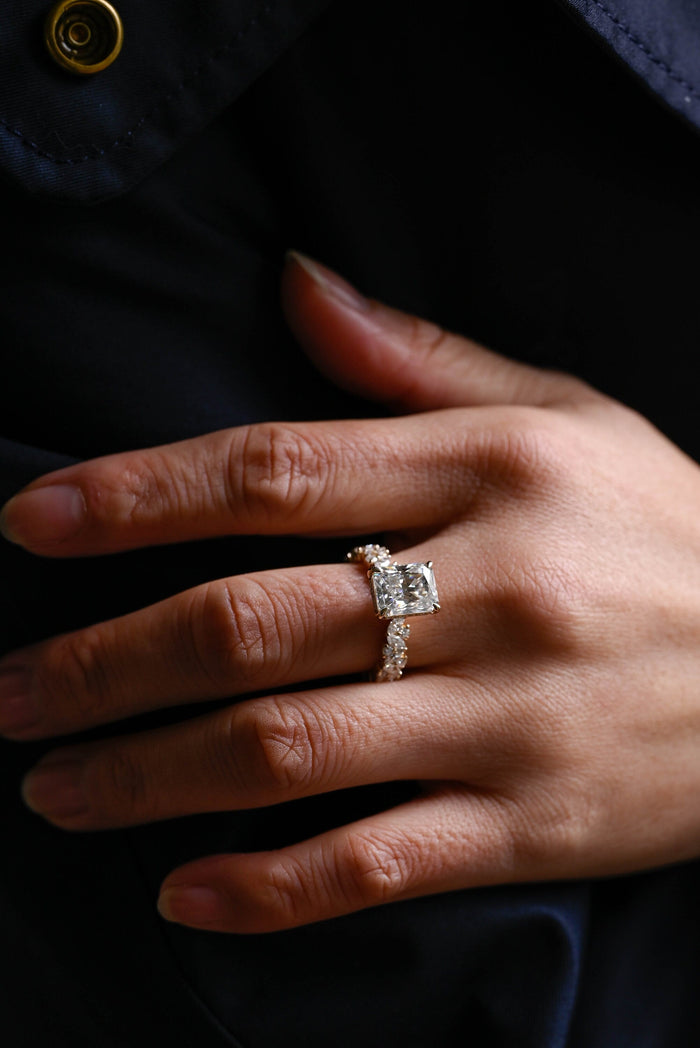 Radiant cut moissanite hidden halo engagement ring in four claws with a band of scattered marquise and round stones in yellow gold, view 2