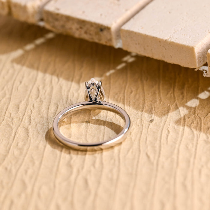 Petite pear moissanite solitaire engagement ring set point up in four claws on a smooth rounded white gold band, view 2