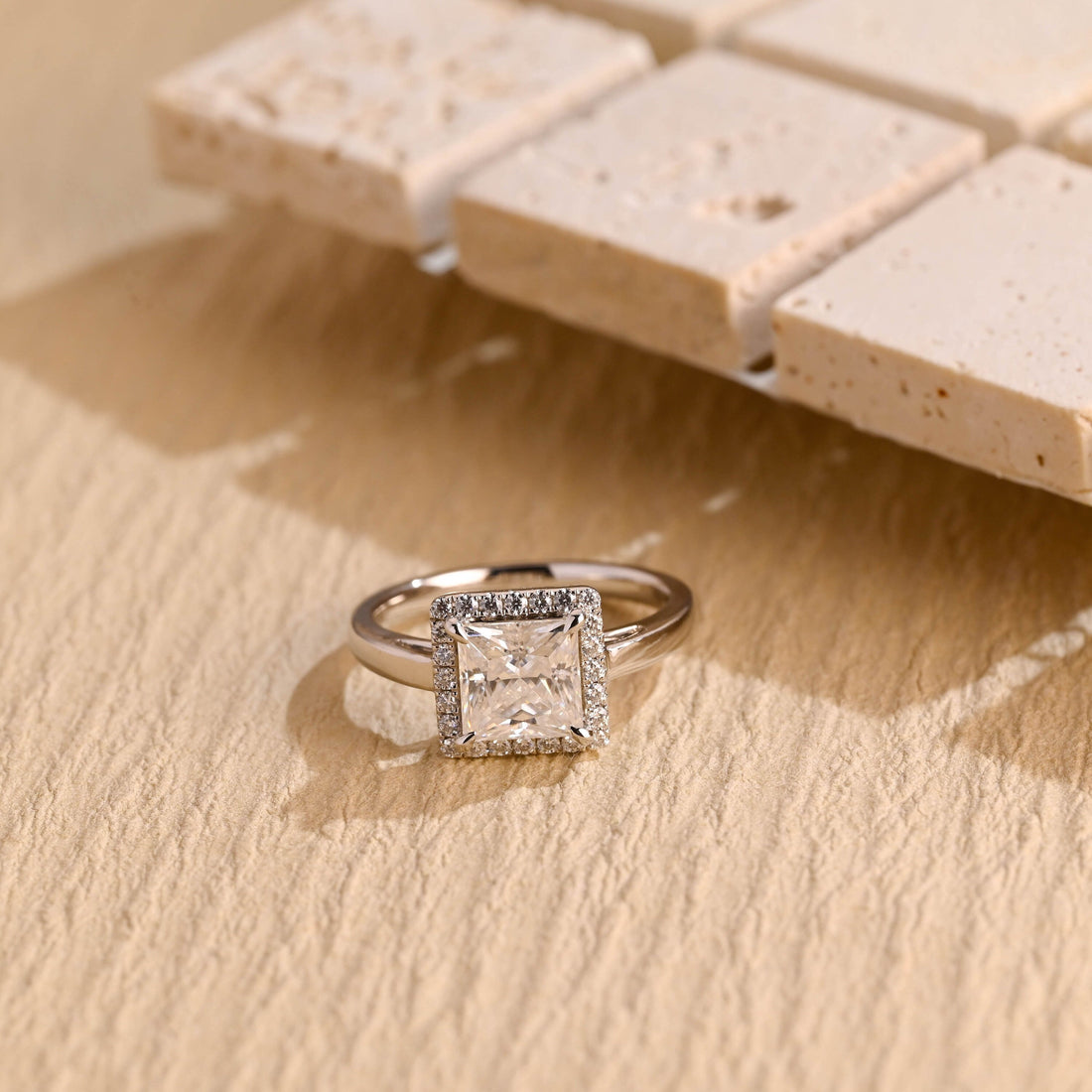 Princess cut moissanite square halo engagement ring on a plain white gold band