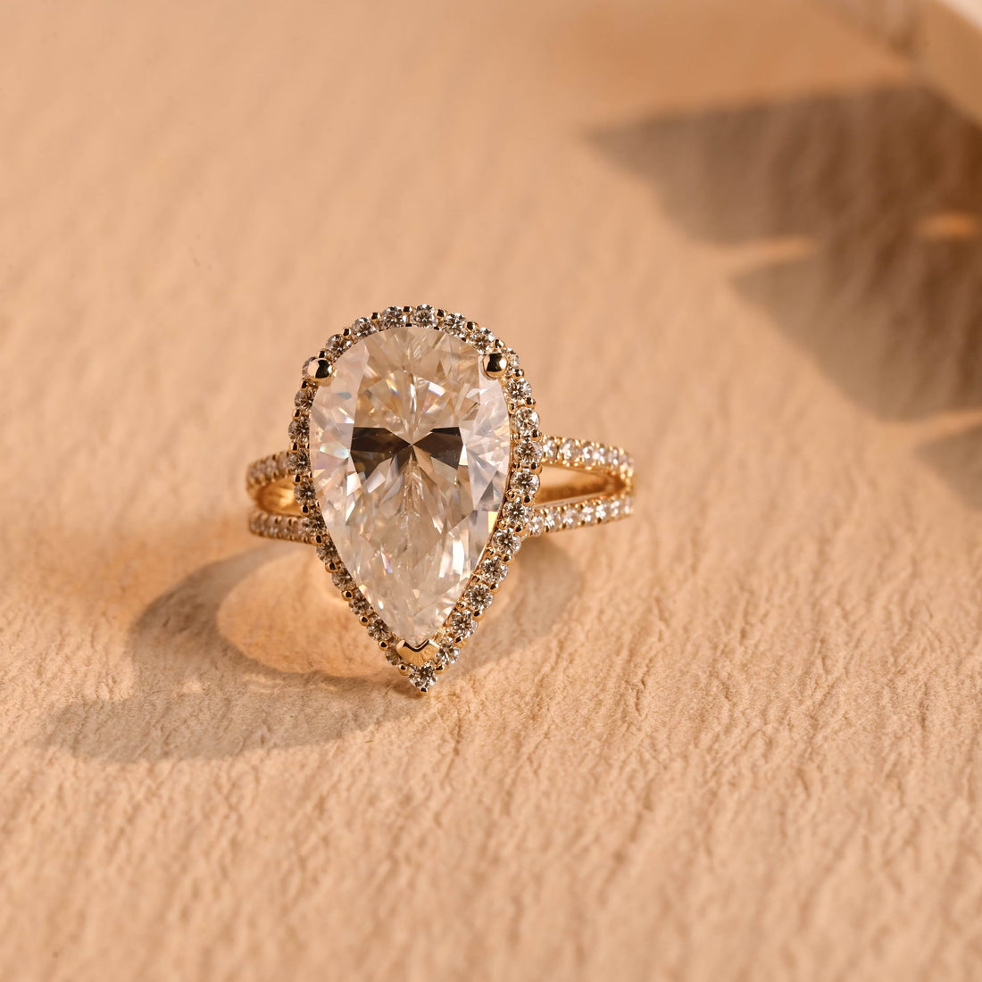 Large pear cut moissanite halo engagement ring with a pave set split shank in yellow gold