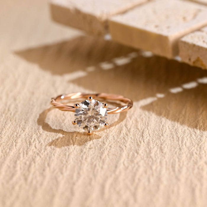 Round moissanite solitaire engagement ring in six ball tipped claws on a slim twisted rope band in rose gold