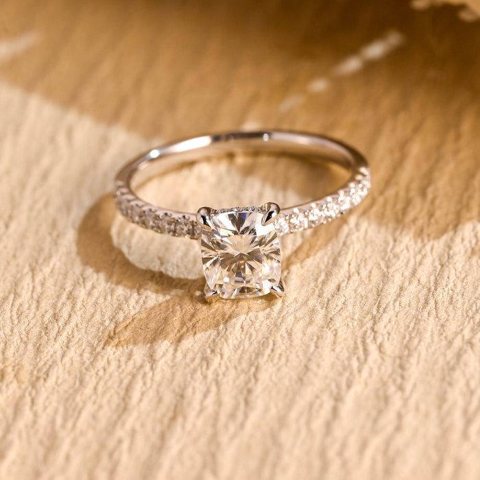 Elongated cushion moissanite hidden halo engagement ring in four claws on a slim white gold band pave set with small round stones