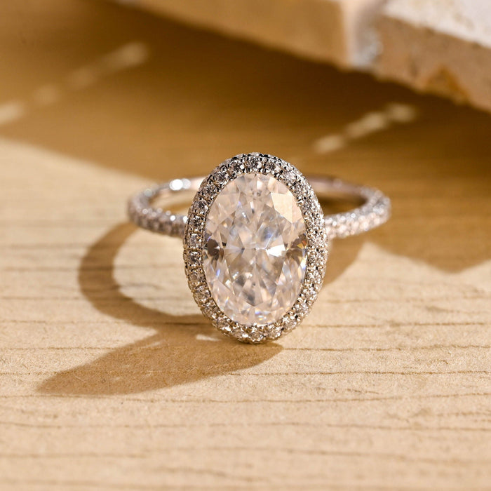 Elongated oval moissanite micro pave halo engagement ring with a band set with tiny stones across the top and down both sides in white gold