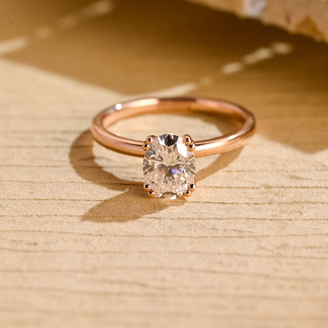 Oval moissanite solitaire engagement ring with four double bead claws on a slim plain polished rose gold band