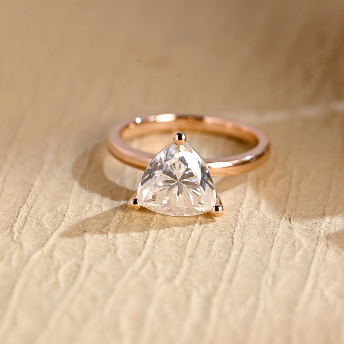 Trillion cut moissanite three claw solitaire engagement ring on a slim polished rose gold band