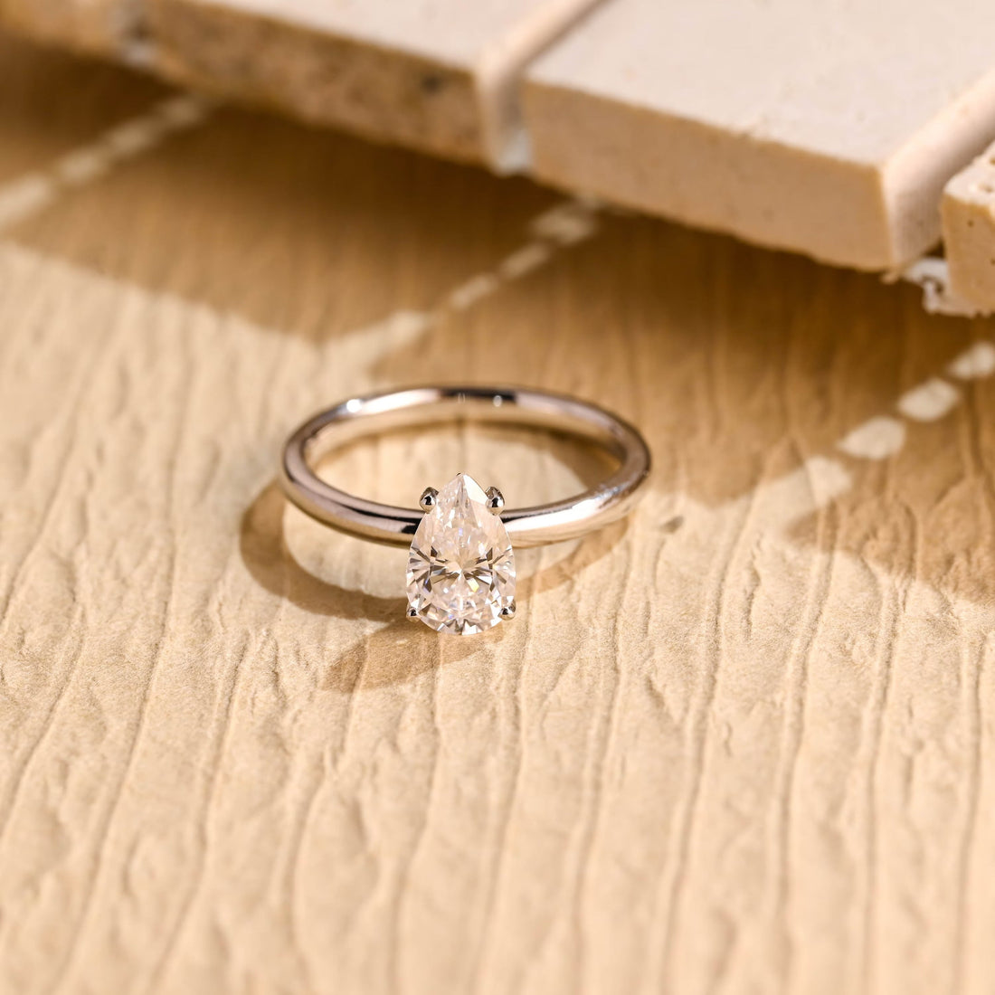 Classic pear cut moissanite solitaire engagement ring in fine claws on a plain polished round white gold band