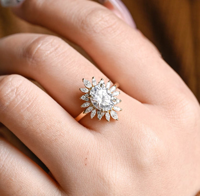 Oval moissanite sunflower halo engagement ring with radiating marquise petals and small round stone clusters on a slim plain yellow gold band, view 2