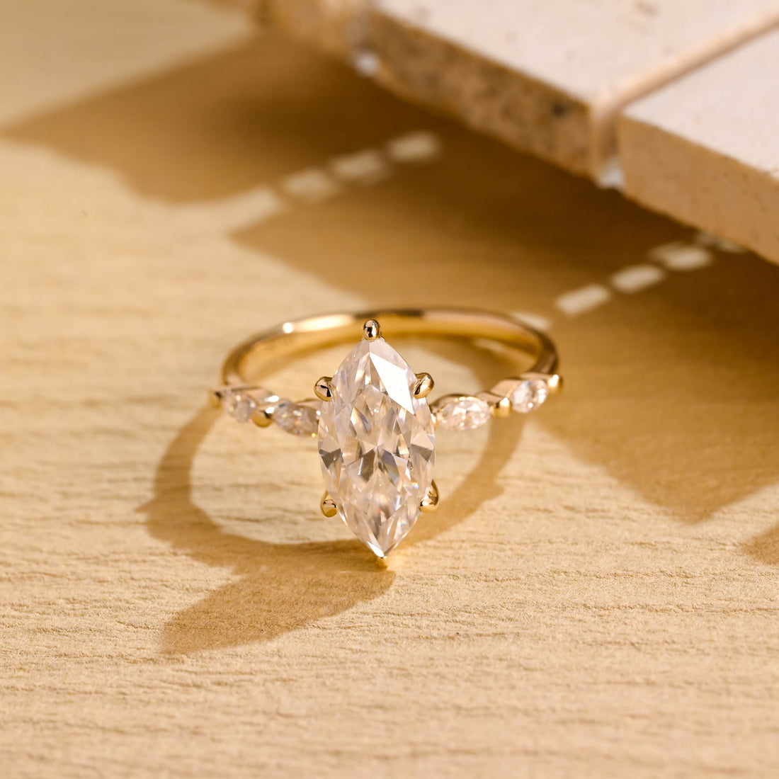Marquise moissanite engagement ring held by six claws with small marquise accent stones set along a slim polished yellow gold band