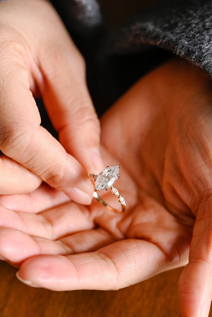 Marquise moissanite engagement ring held by six claws with small marquise accent stones set along a slim polished yellow gold band, view 2
