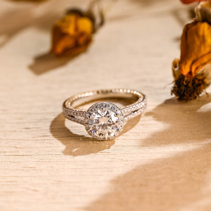 Round moissanite halo engagement ring with a split shank band, both strands pave set with tiny round stones, in white gold
