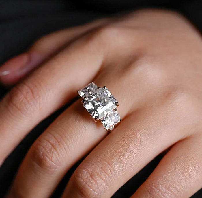 Radiant cut moissanite three stone engagement ring with two radiant side stones in four claws on a pave set white gold band, view 2