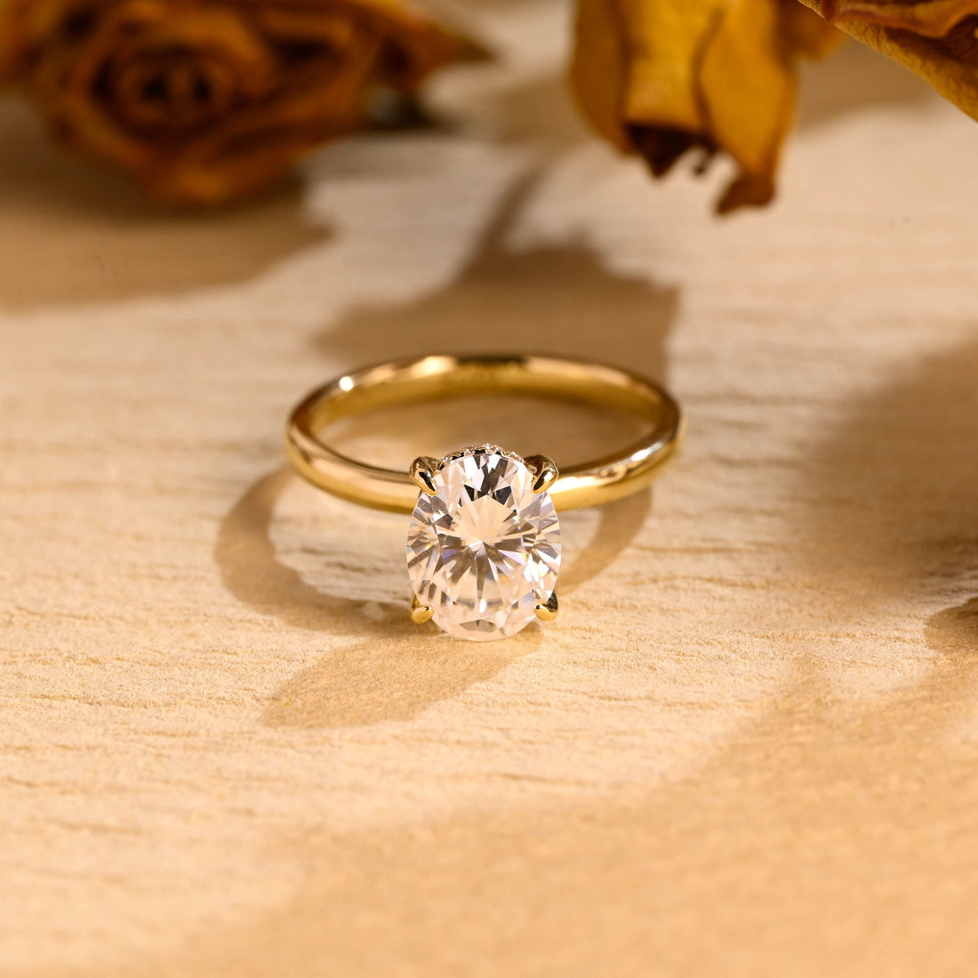 Oval moissanite hidden halo solitaire engagement ring with four claws on a plain polished round yellow gold band