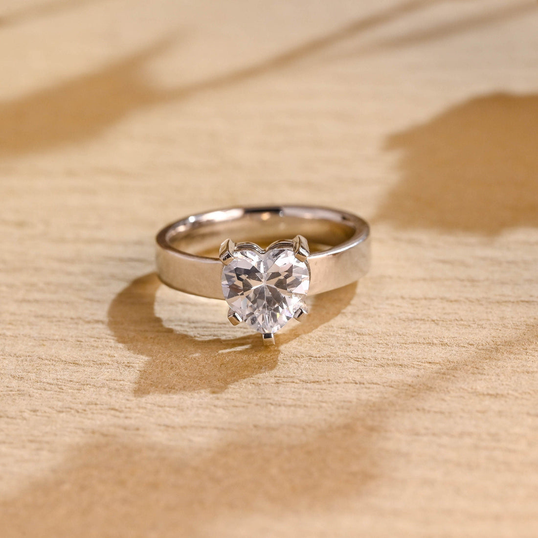Heart cut moissanite solitaire engagement ring on a wide flat polished white gold band