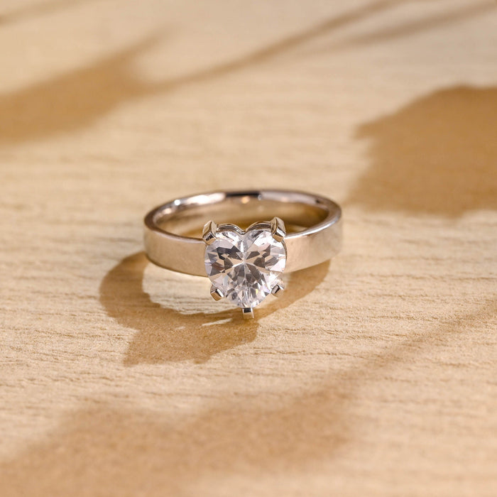 Heart cut moissanite solitaire engagement ring on a wide flat polished white gold band