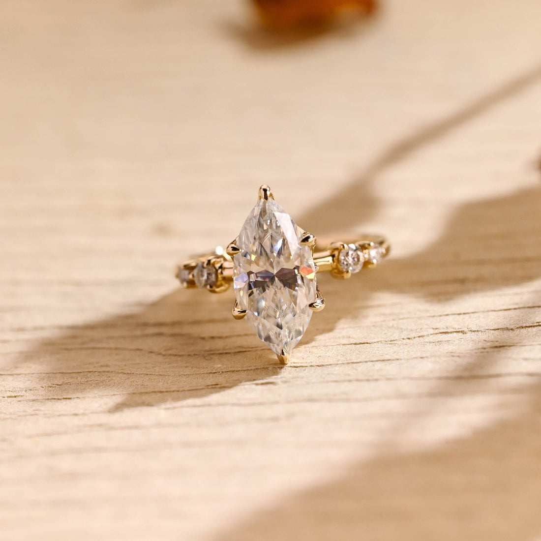 Marquise cut moissanite six claw engagement ring on an organic twig style yellow gold band with claw set round stones on the shoulders