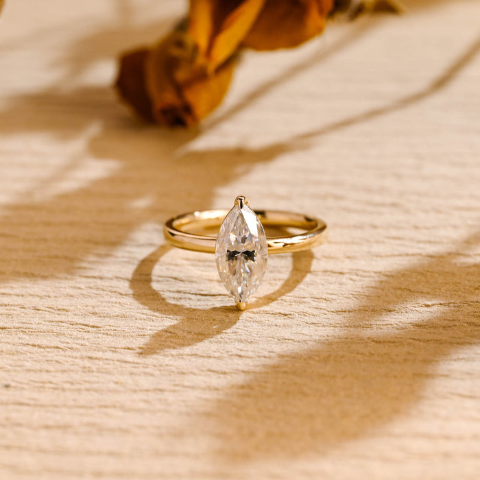 Minimalist marquise cut moissanite solitaire ring with V tip claws on a slim plain yellow gold band