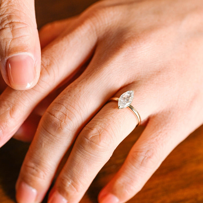 Minimalist marquise cut moissanite solitaire ring with V tip claws on a slim plain yellow gold band, view 2
