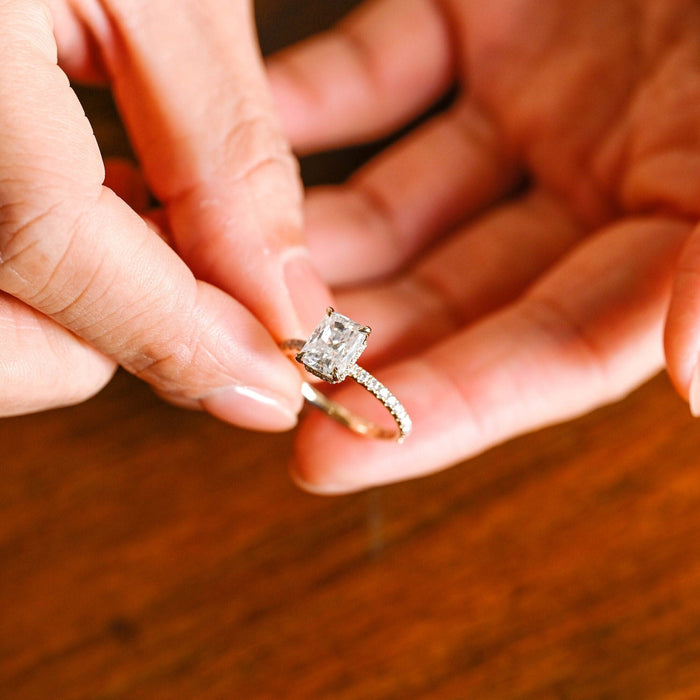 Radiant cut moissanite hidden halo engagement ring in four claws with a slim shared prong pave set yellow gold band, view 2