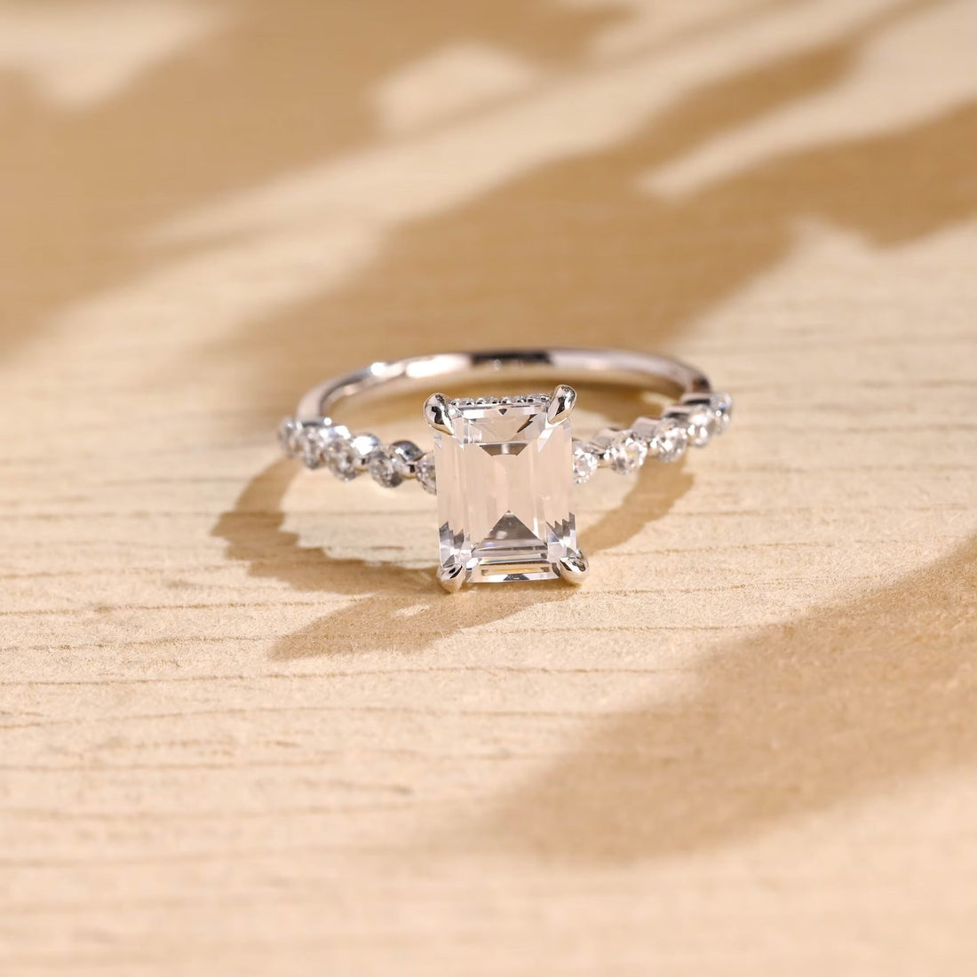 Emerald cut moissanite hidden halo engagement ring with individually spaced round stones along a slim white gold band