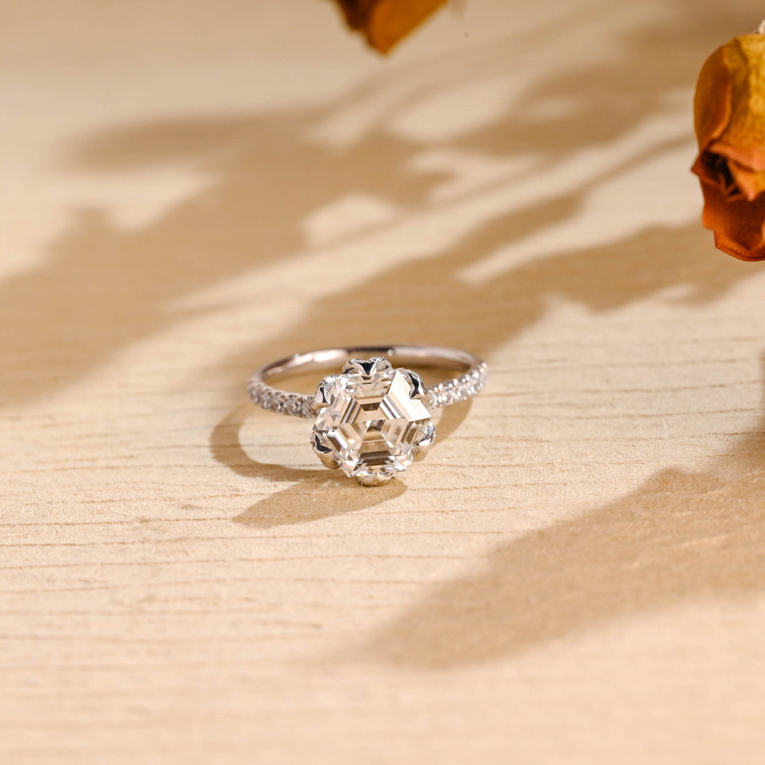 Hexagon cut moissanite tulip style solitaire engagement ring with petal claws on a pave set white gold band